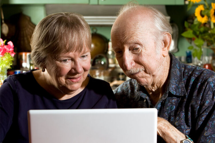 Nainen ja vanha mies tietokoneen näytön äärellä.