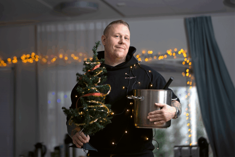 Ohjaaja Elovaara kädessään iso puurokattila ja pikkukuusi.