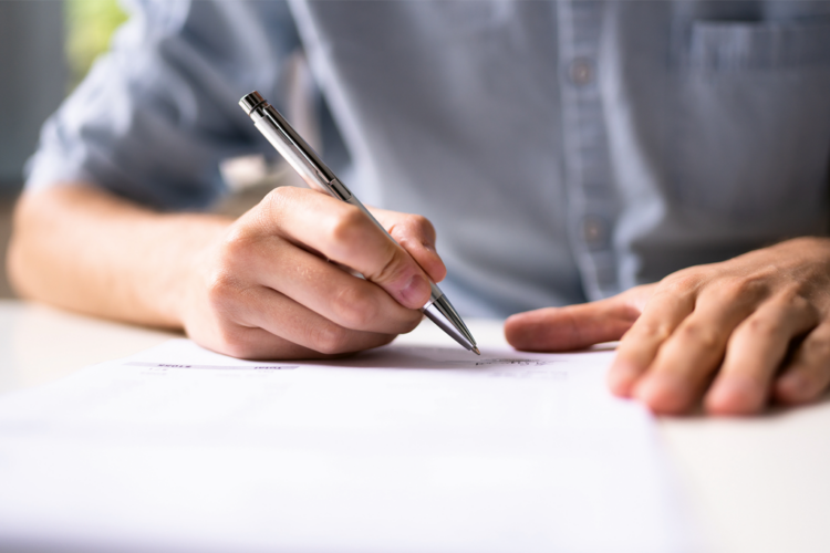 Kädet, kynä ja paperi.